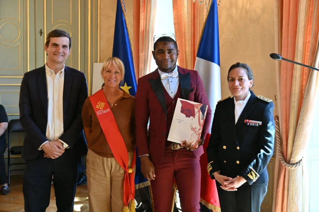 Photo de cérémonie de naturalisation : un participant tenant son dossier entouré de représentants de l'administration